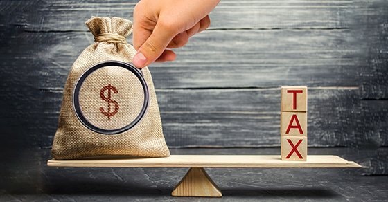 money bag and tax written on blocks on a scale