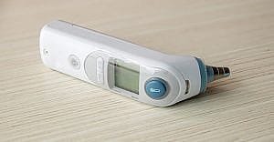 medical ear thermometer isolated on wooden table. Digital thermometer for baby.