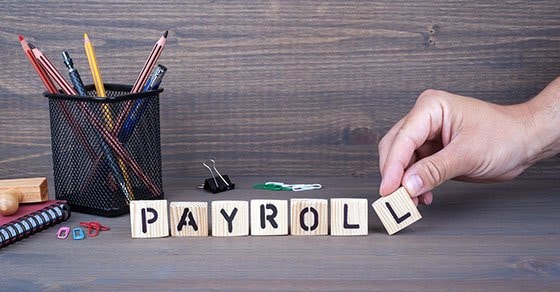 payroll. Wooden letters on dark background