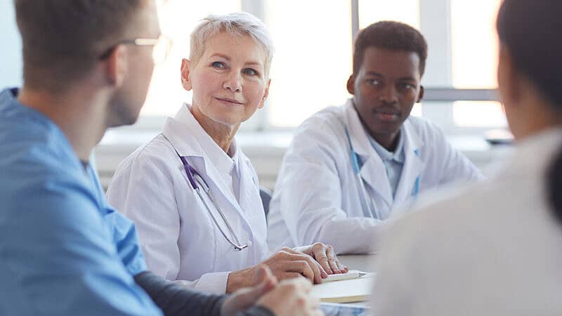 Multi,Ethnic,Group,Of,Doctors,Sitting,At,Table,,Focus,On Multi,Ethnic,Group,Of,Doctors,Sitting,At,Table,,Focus,On
