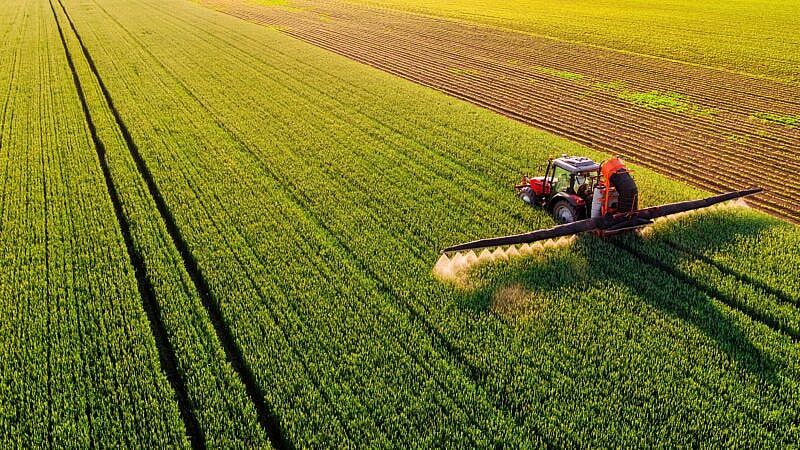 Drone,Shot,Of,A,Tractor,Spraying,In,Lush,Green,Wheat