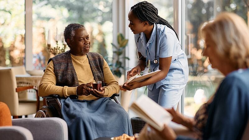 Young,Nurse,Communicating,With,Senior,Man,Who,Is,Sitting,In