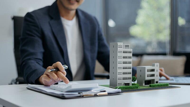 Home,Loan,Officer,Uses,A,Calculator,With,A,House,Plan