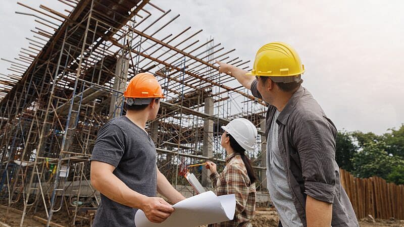 Team,Of,Construction,Workers,Discussing,Project,Details,With,Blueprint,In