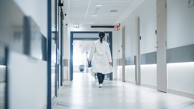 Female,Doctor,Walking,Away,In,An,Empty,Hospital,Hallway.,General